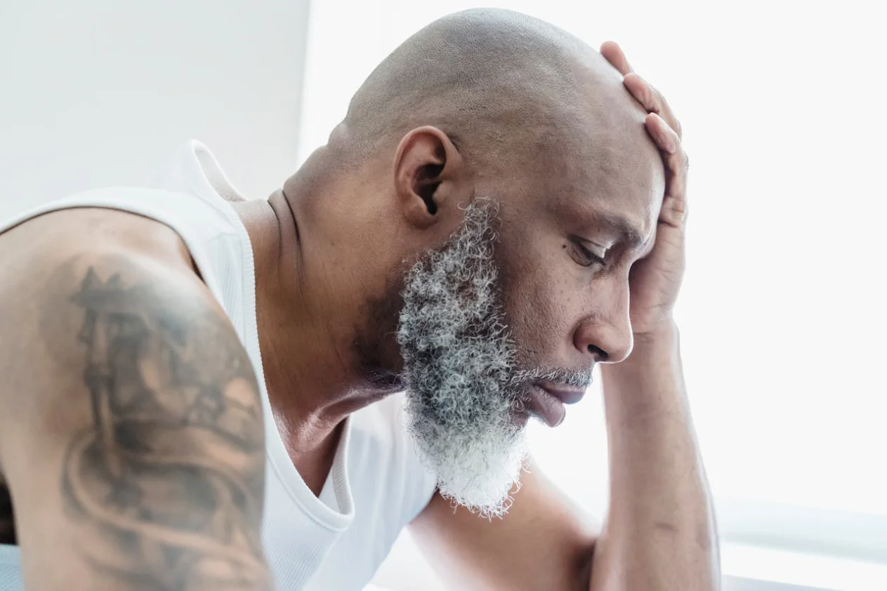 A bald headed man in front of a window