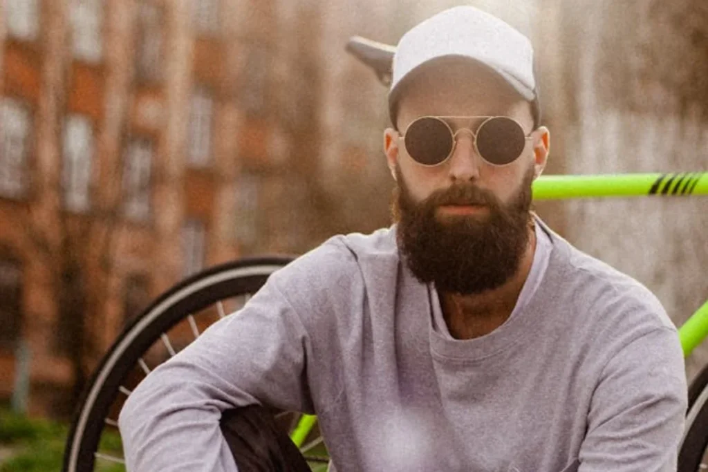 A young man with sunglasses, cap, and a bicycle