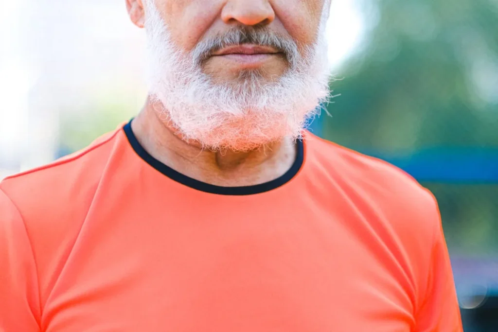 An old man with a beard and an orange t-shirt