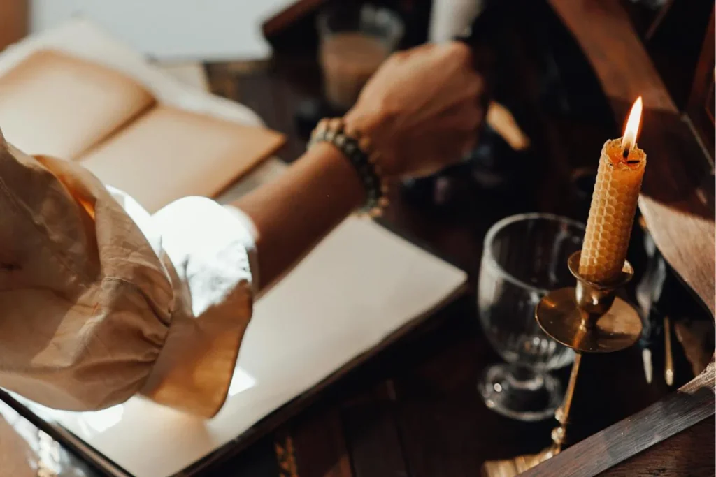 A person is writing and illuminate with a beeswax candle