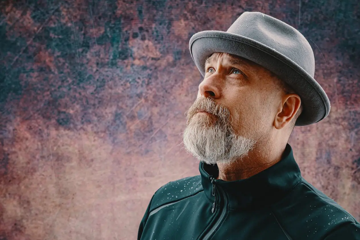 a middle-aged man with a hat and a graying beard