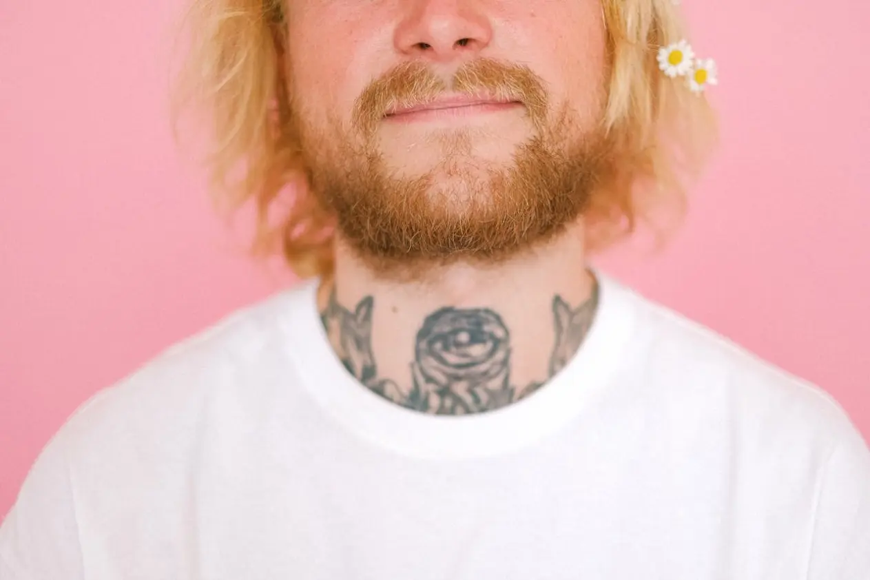 a man with a short beard on a pink background