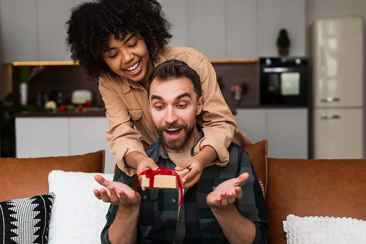 woman giving a surprise gift to her boyfriend