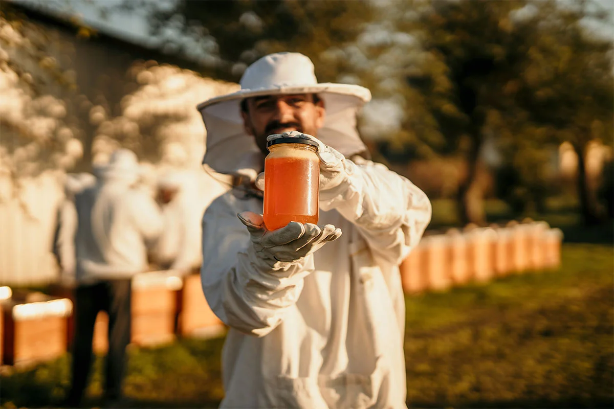a beekeeper with a jar of honey in his hands