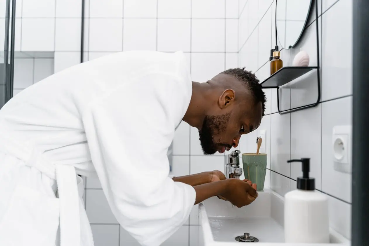 a man in a bathrobe washing his face