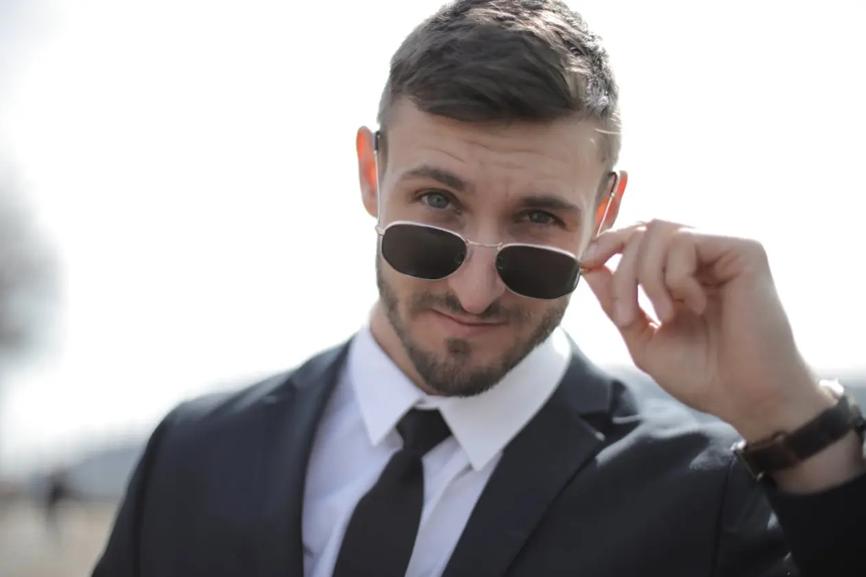 Man in suit lowering his sunglasses so his eyes can be seen