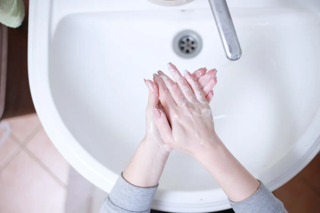 Top view of a sink with hands applying liquid soap