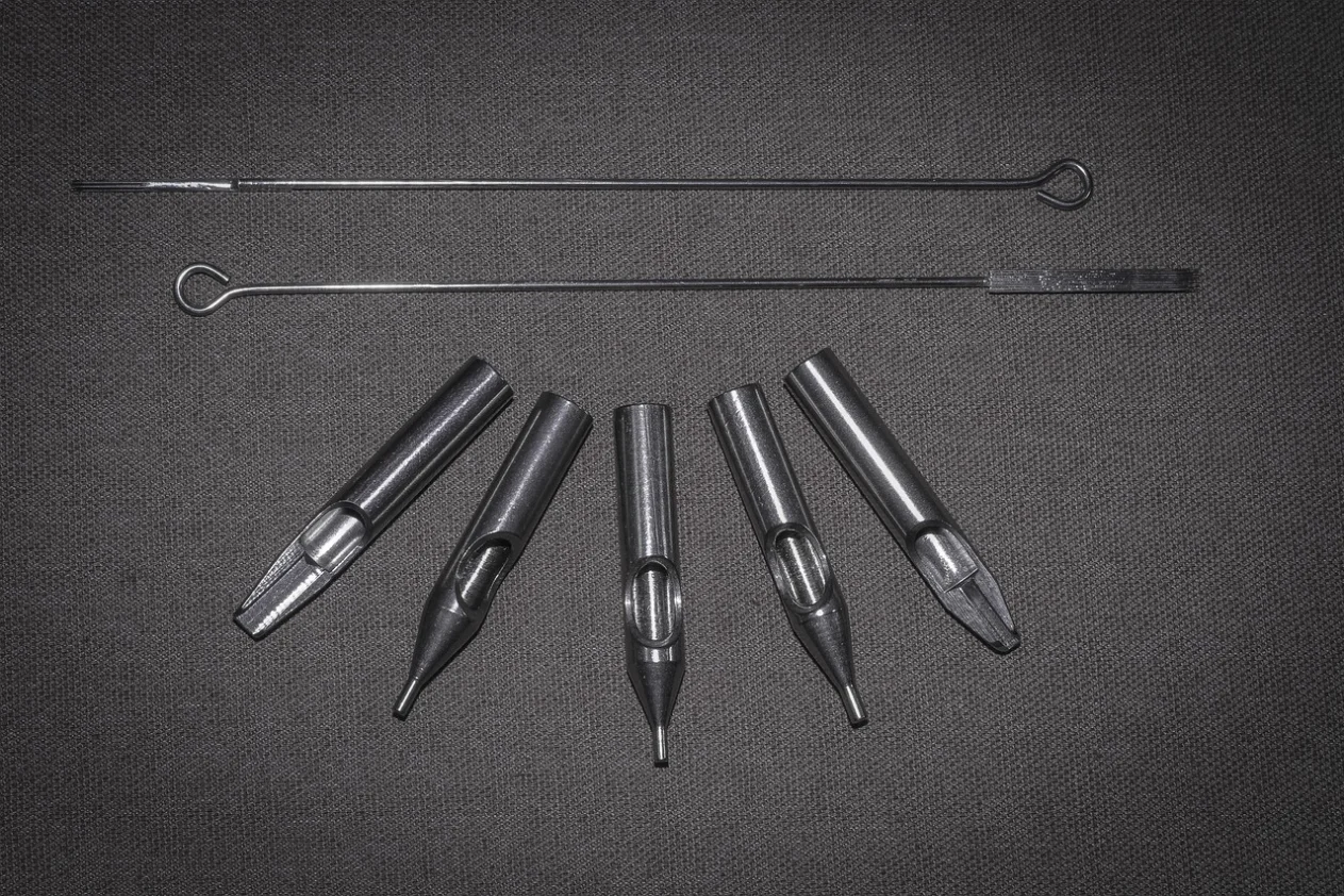 2 needles and 5 nozzles for tattooing on a gray surface.